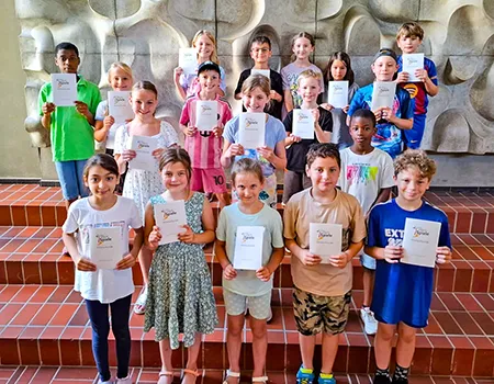 Schülerinnen und Schüler eines Jahrgangs halten ihre Ehrenurkunden des Sportfestes nach der Verleihung in der Aula