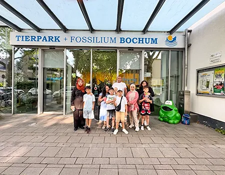 Die Teilnehmer:innen des Ausflugs stehen in einem Gruppenbild vor dem Eingang des Tierparks in Bochum