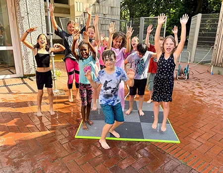 Schülerinnen und Schüler toben in den Pausen zur Abkühlung auf den Wassermatten
